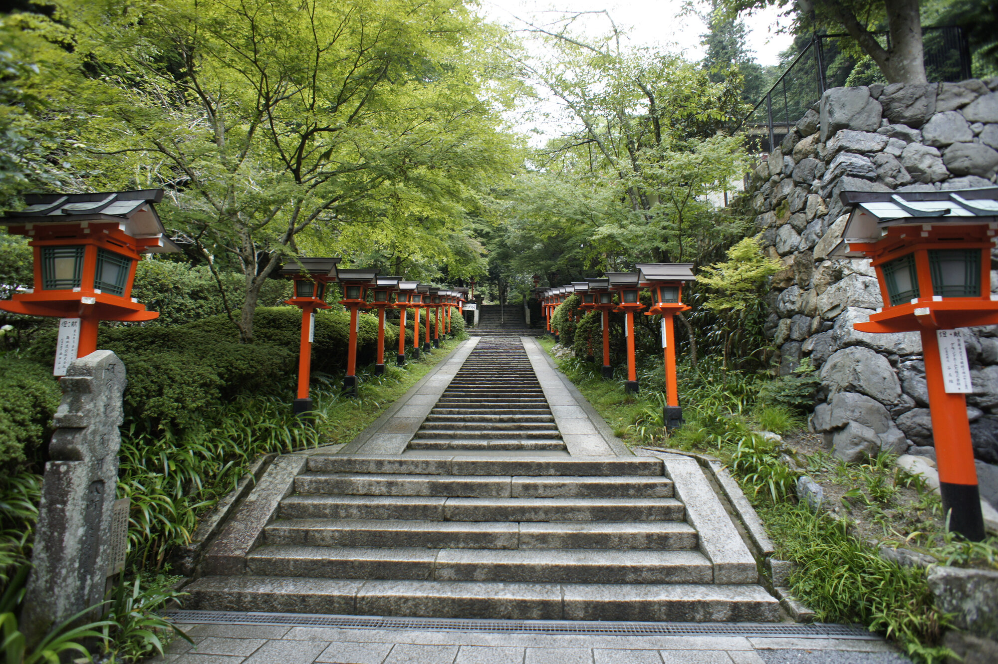 Steinerne Treppe mit roten Holzlaternen am Aufgang zum Kurama-Tempel bei Kyōto