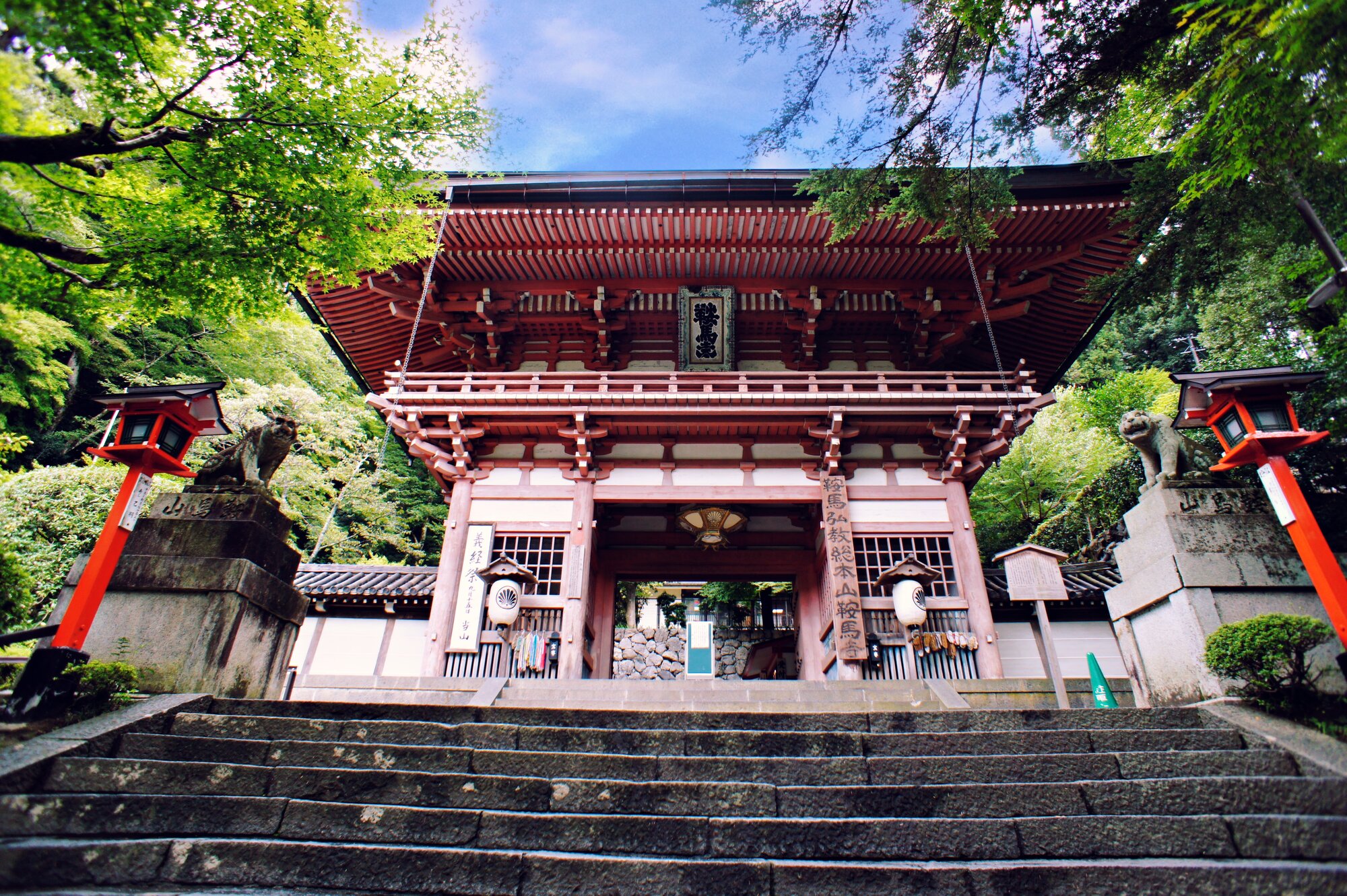 The red Niōmon entrance gate of Kurama Temple near Kyōto, photographed from below with stone steps leading up
