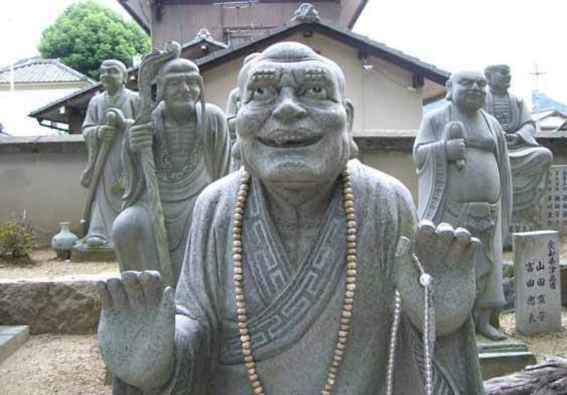 Lachende Buddha-Statue mit Mala-Kette in einem japanischen Tempelhof