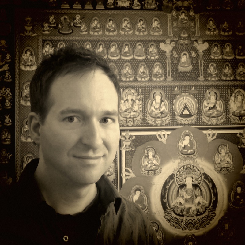 Dr. Mark Hosak in Sepia-Tönen vor einem japanischen Mandala-Schrein mit Buddha-Darstellungen